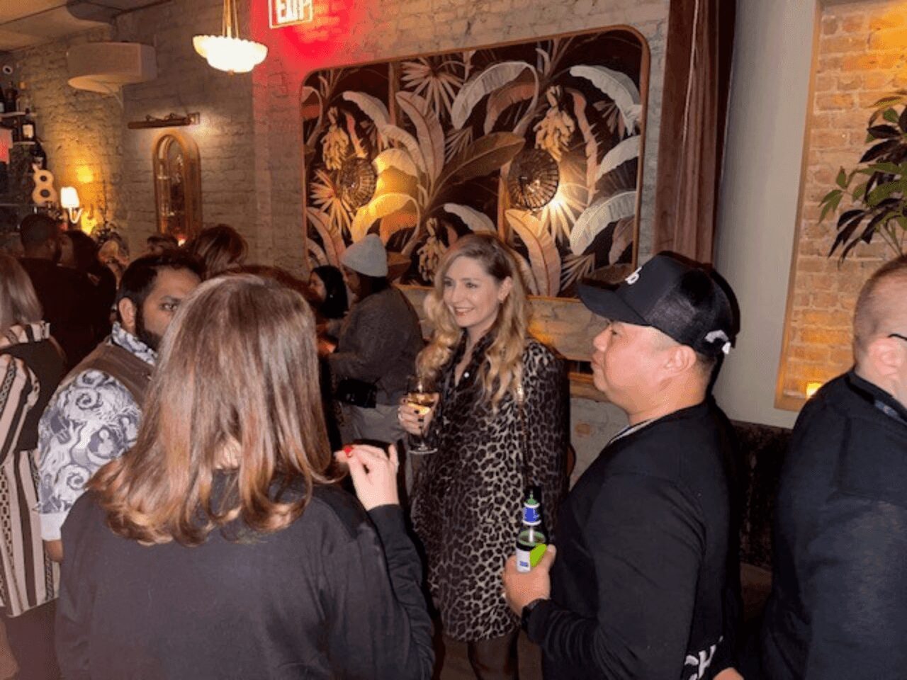 People socializing indoors, one woman in a leopard print coat.