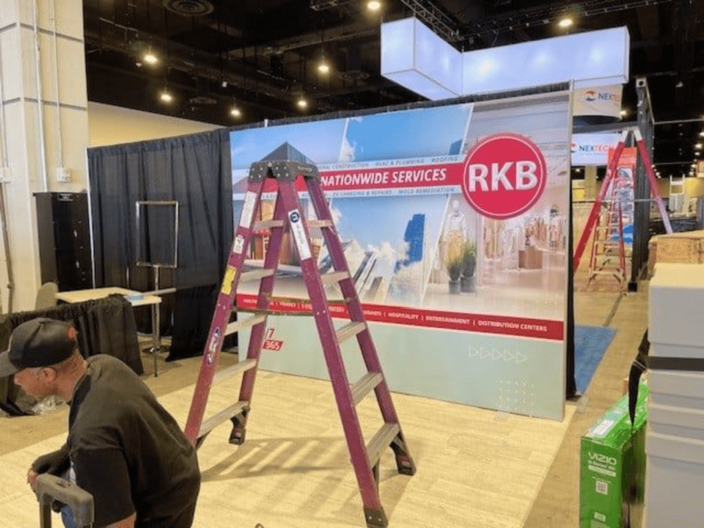 Ladder in front of RKB booth at a convention center.